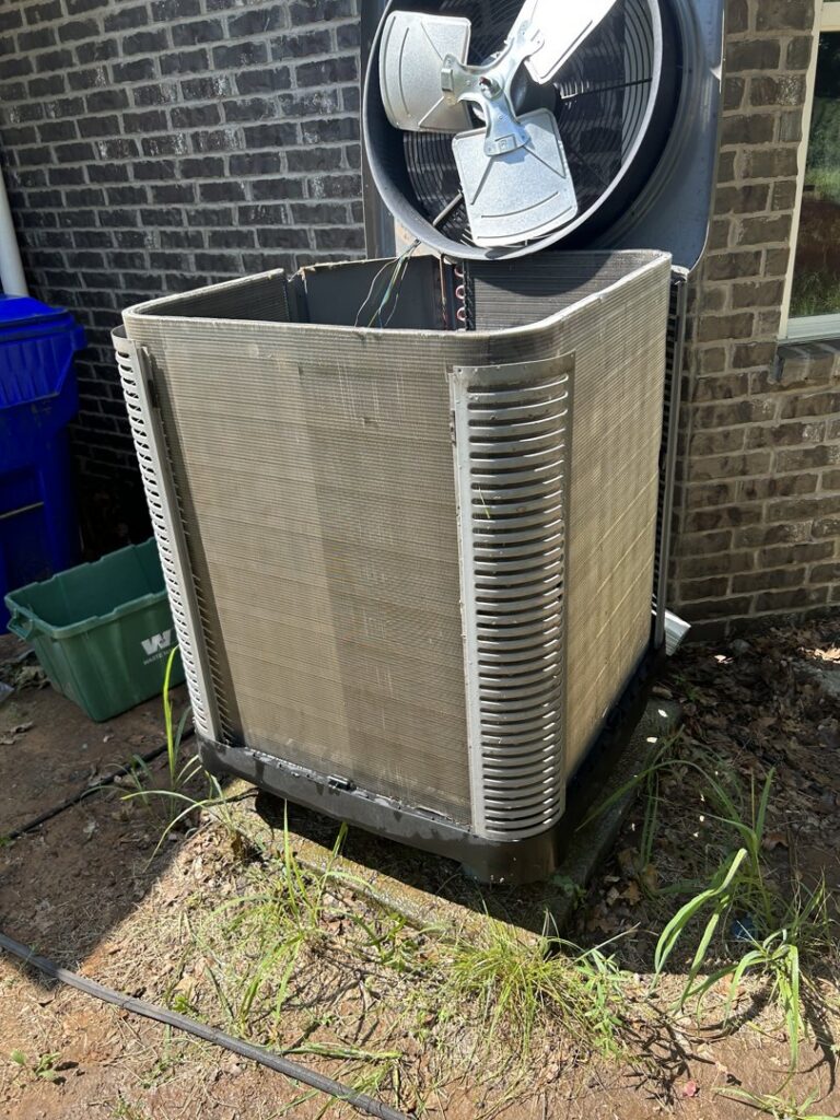 An outdoor AC unit undergoing maintenance with its top fan removed by Oklahoma Climate Solutions in Oklahoma City, OK.