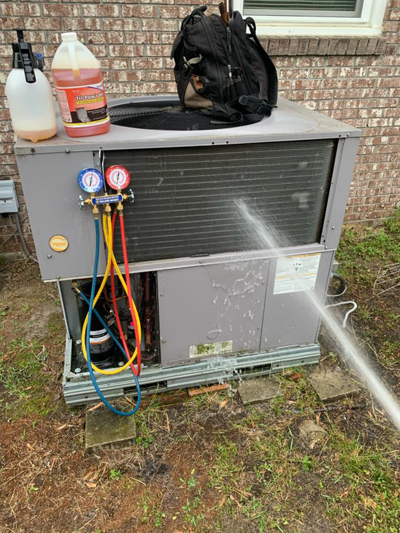 An outdoor AC unit undergoing maintenance and cleaning with gauges attached by Lbz Construction in Charleston, SC