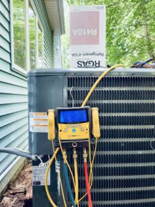 An outdoor air conditioning unit with refrigerant gauges connected, indicating a charge or diagnostic service by HVAC Fellows in Boston, MA.