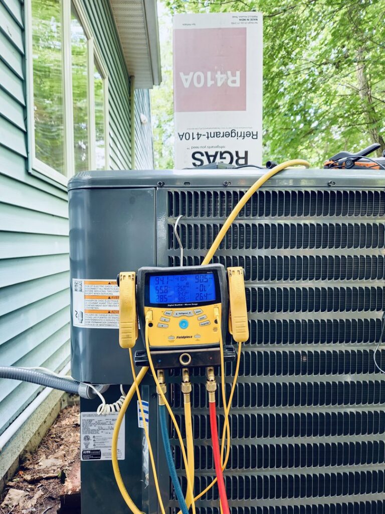 An outdoor air conditioning unit with refrigerant gauges connected, indicating a charge or diagnostic service by HVAC Fellows in Boston, MA.