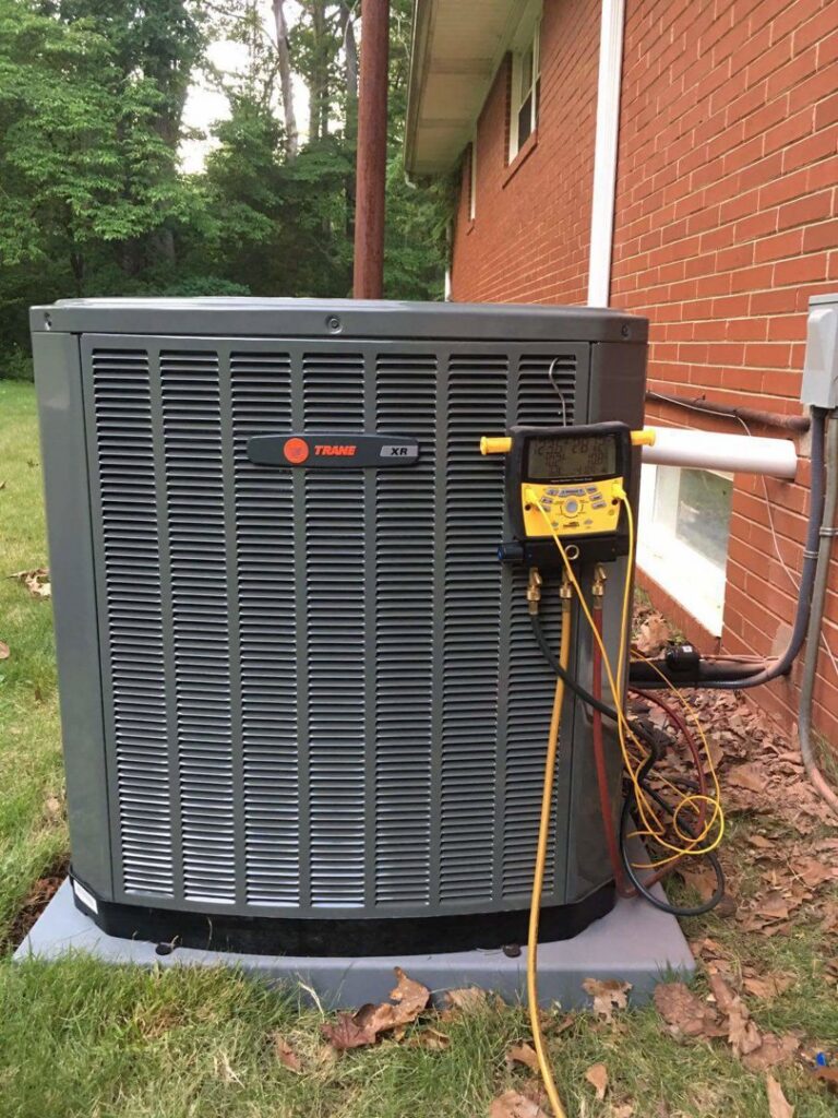 An outdoor AC unit undergoing a refrigerant check with gauges by Fred's Heating And Cooling in Charlotte, NC