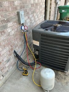 An HVAC technician performing a refrigerant check on an outdoor AC unit for Oklahoma Climate Solutions in Oklahoma City, OK.