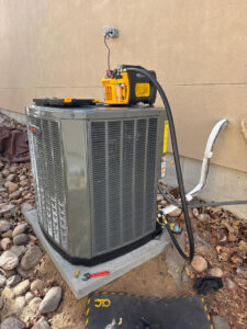 An outdoor AC unit undergoing refrigerant service with a vacuum pump and gauges by Primary Air Home Services in Aurora, CO.
