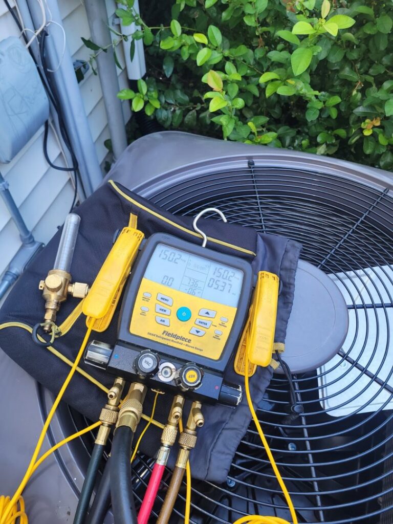 Refrigeration gauges connected to an outdoor air conditioning unit during service by JJJ Techs Heating and Cooling in Kinzers, PA.