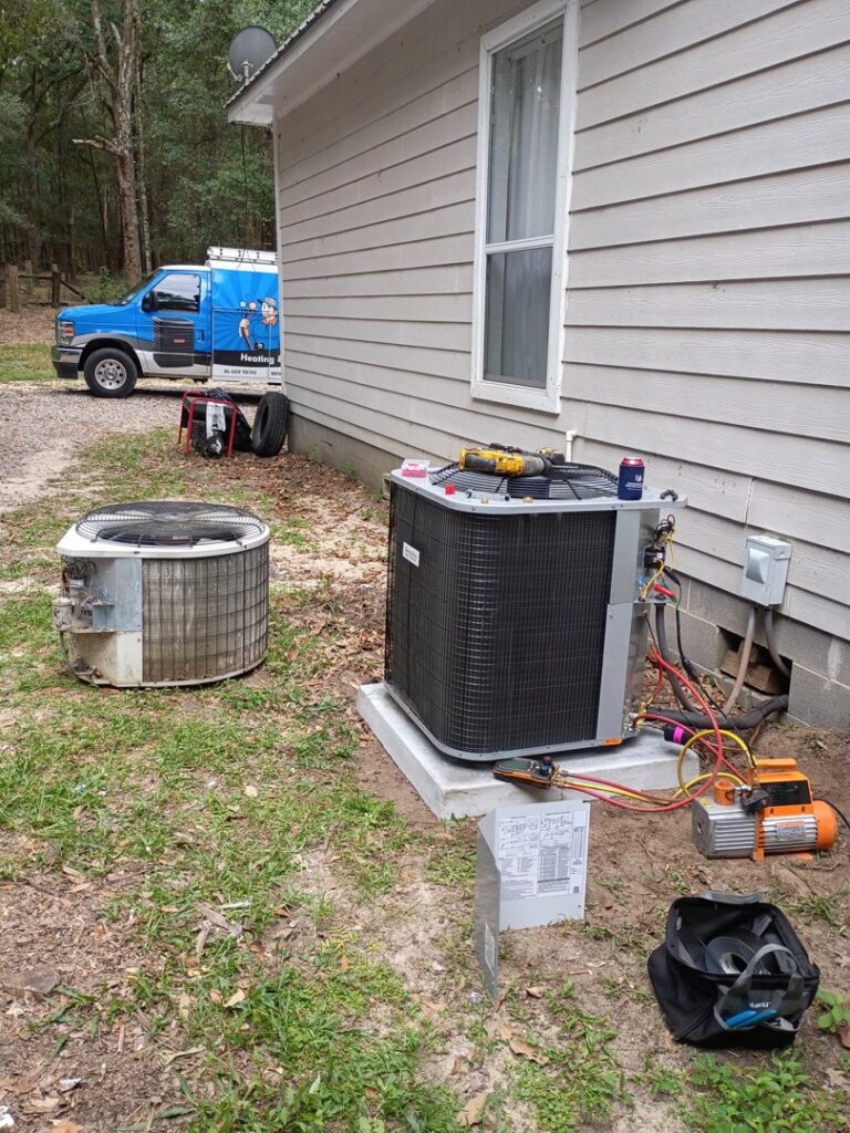 An old air conditioning unit being replaced with a new one, showing tools and a service van from Netherland Air Conditioning LLC in Mobile, AL.