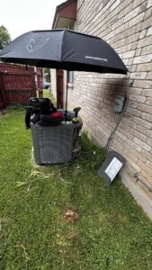 An outdoor AC unit being serviced under an umbrella during a service call by Bree HVAC Contractor in Cedar Park, TX.
