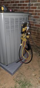 An outdoor air conditioning unit being serviced with gauges connected by Peach Tree HVAC in Frederick, MD.
