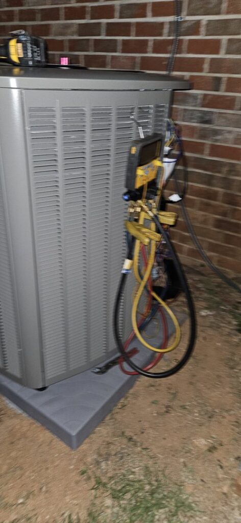 An outdoor air conditioning unit being serviced with gauges connected by Peach Tree HVAC in Frederick, MD.
