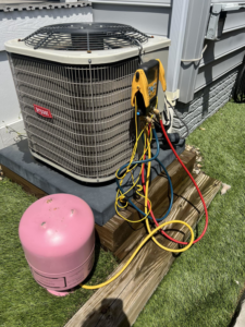 An outdoor Bryant AC unit being serviced with gauges and a refrigerant tank by Buckeye Mechanical Construction in Columbus, OH.