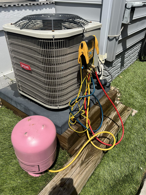 An outdoor Bryant AC unit being serviced with gauges and a refrigerant tank by Buckeye Mechanical Construction in Columbus, OH.