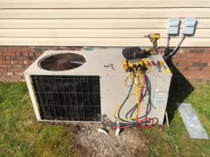 An outdoor air conditioning unit being serviced with refrigerant gauges by G&G Heating and Air in Portage, MI.