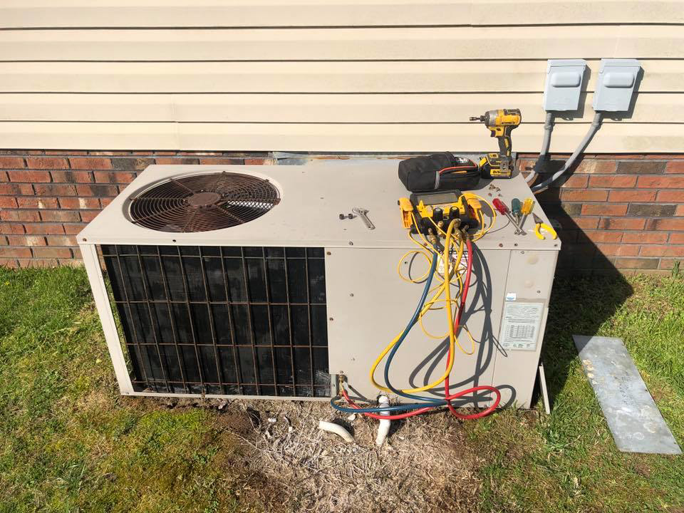 An outdoor air conditioning unit being serviced with refrigerant gauges by G&G Heating and Air in Portage, MI.