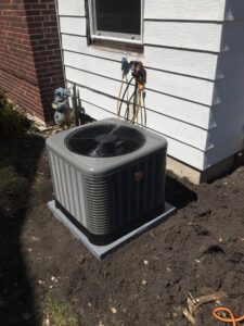 An outdoor air conditioning unit being serviced with gauges connected by The Heating Guys in Fargo, ND.