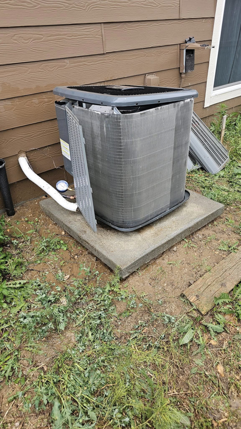 An outdoor AC unit with its side panel removed, showing coils, indicating service or repair by Erik's Quality HVAC LLC in Greeley, CO.