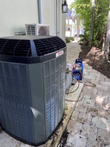 An outdoor AC unit with refrigerant gauges and tools, indicating service by T&D Air Conditioning in Fort Lauderdale, FL.