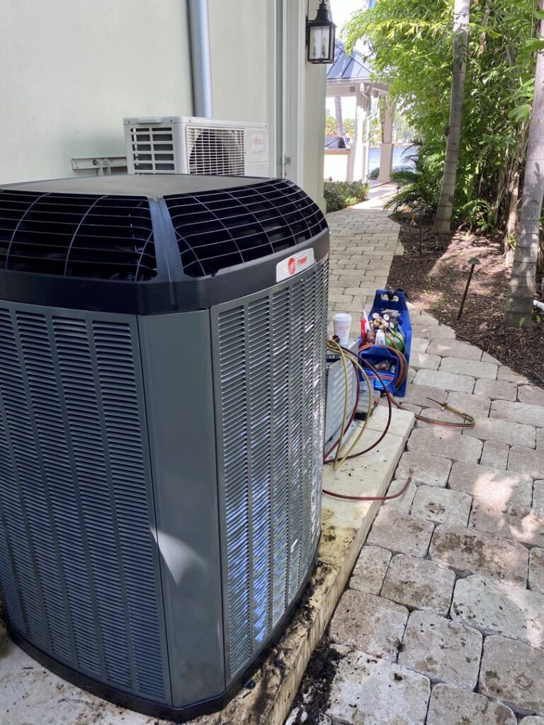 An outdoor AC unit with refrigerant gauges and tools, indicating service by T&D Air Conditioning in Fort Lauderdale, FL.