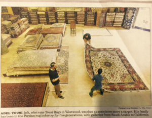 Adel Tousi and associates moving a large patterned carpet in the showroom of Tousi Rugs in Los Angeles, CA.