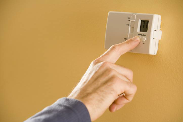 A hand adjusting a digital thermostat for optimal home comfort with B K Heating in Leavenworth, KS.