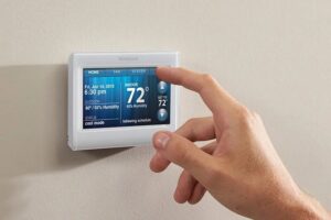A hand adjusting a Honeywell smart thermostat, showing HVAC system control, by McCarthy's One Hour Heating & Air Conditioning in Omaha, NE.