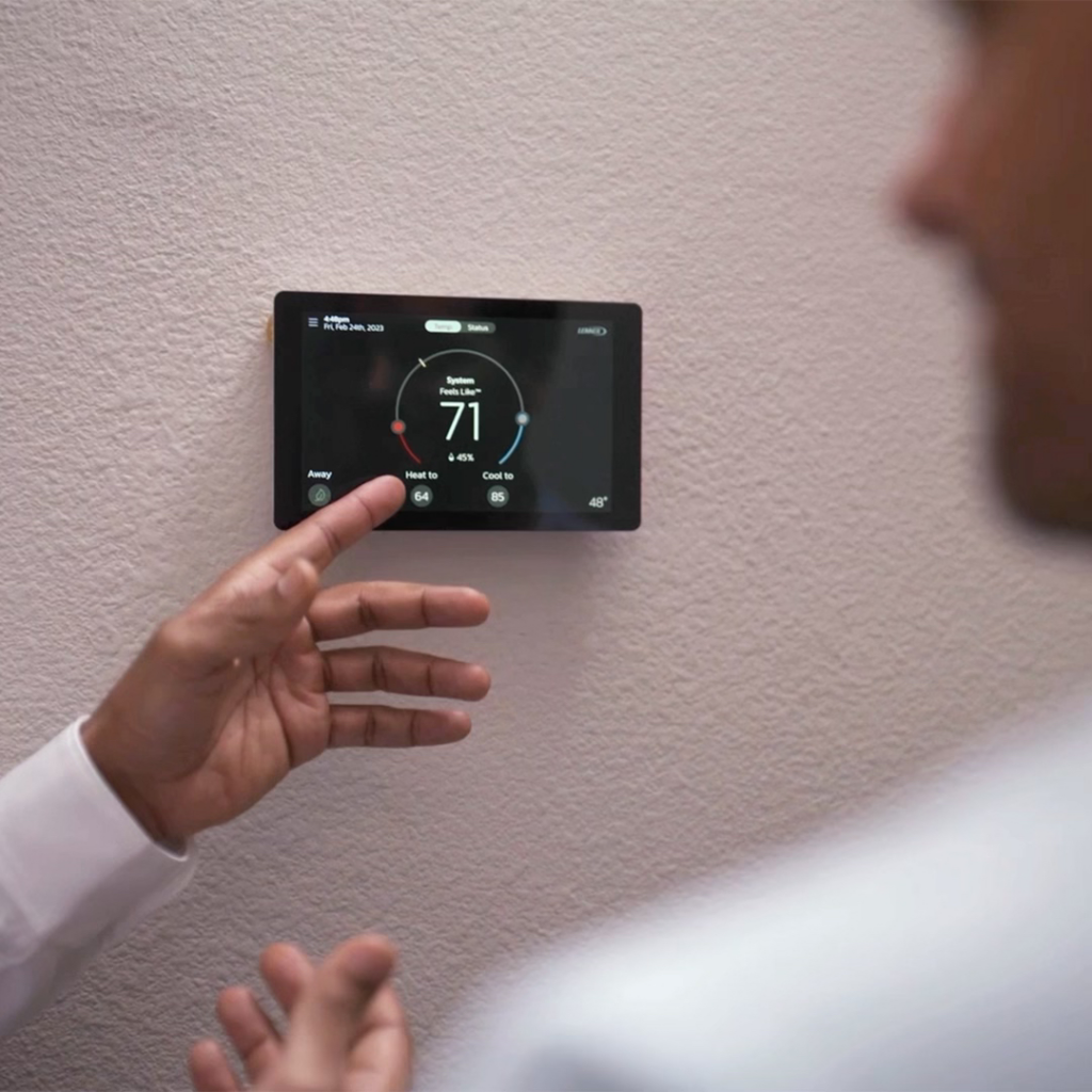 A person adjusting a smart thermostat on a wall, showing heating and cooling settings, by Total Comfort, Inc. in Danbury, CT