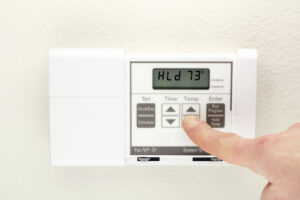 A hand adjusting a digital thermostat for home comfort, serviced by Boykin Air Conditioning Services in Sumter, SC.