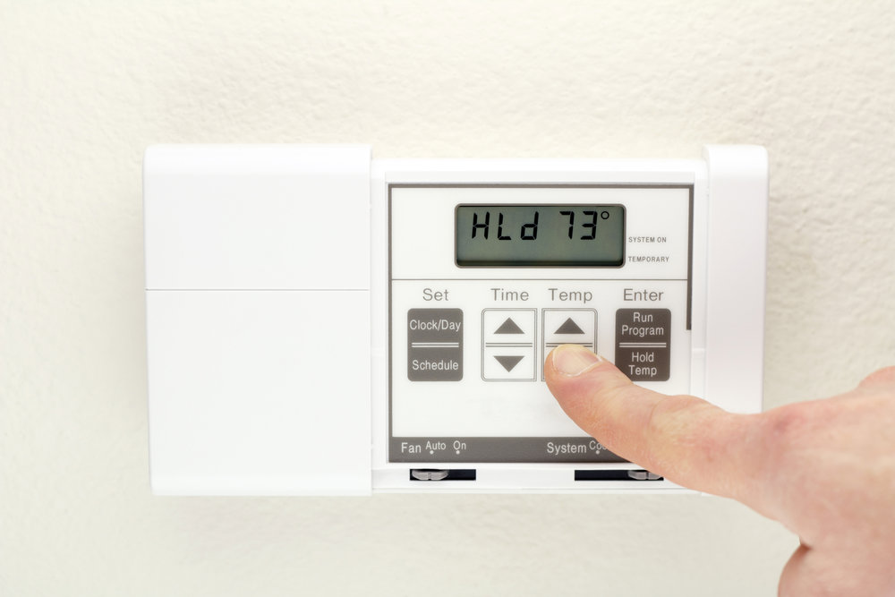 A hand adjusting a digital thermostat for home comfort, serviced by Boykin Air Conditioning Services in Sumter, SC.