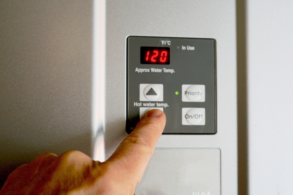 A hand adjusting the water heater temperature on a control panel at Vassar's Service of Richmond in Richmond, VA