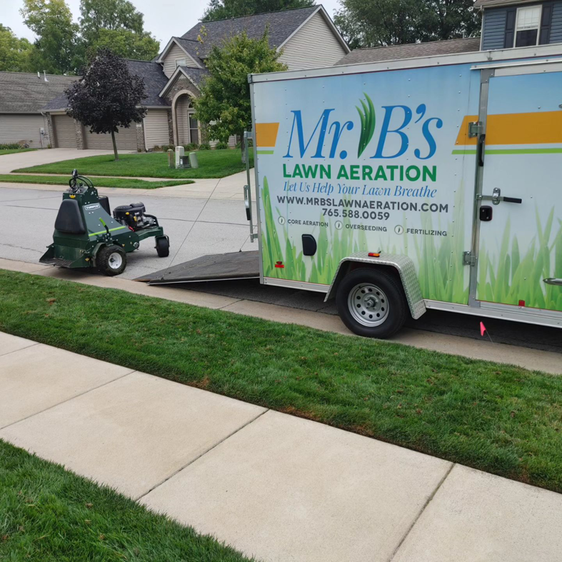 A lawn aeration machine being loaded onto a branded trailer for Mr. B's Lawn Aeration in Lafayette, IN.