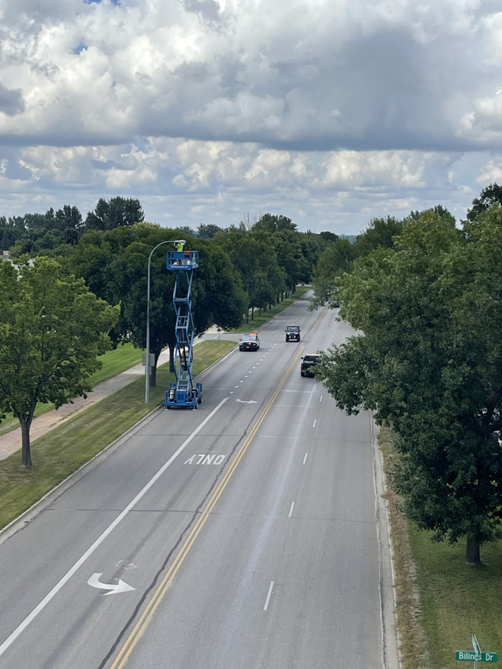 An aerial view of an electrician from On Point Electrical Services working on a street light in Williston, ND.