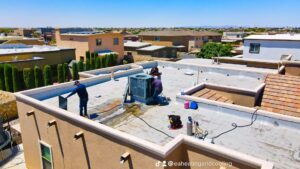 An aerial view of two HVAC technicians performing service on a rooftop unit for EA Heating & Cooling in El Paso, TX.