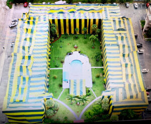 An aerial view of a large building complex covered in yellow and blue tarps for pest control fumigation by Shield Pest Control in Homestead, FL.