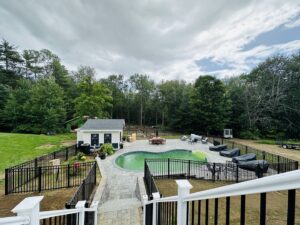 An aerial view showcasing a swimming pool area enclosed by a black aluminum fence by Ultra Fence LLC in Brookline, NH.