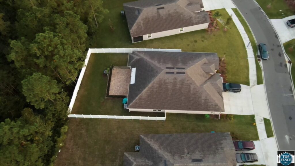An aerial view showcasing a newly installed white fence enclosing a residential backyard by Top Fence LLC in Jacksonville, FL.