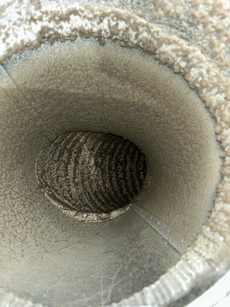 A close-up view inside a very dirty air duct, showing buildup that requires professional cleaning by Primary Air Home Services in Aurora, CO.