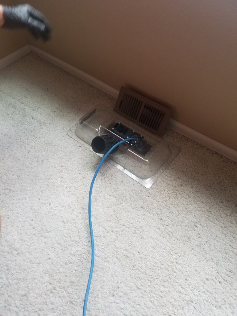 A technician performing air duct cleaning on a carpeted floor with a specialized tool by STC Carpet Care in Arvada, CO
