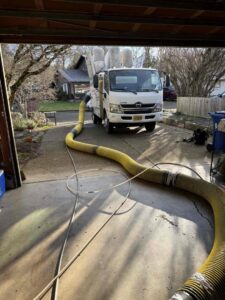 An Alpine Heating air duct cleaning service truck with a hose extending into a garage in Eugene, OR.