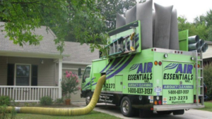 Air Essentials air duct cleaning truck with a hose entering a home in Madison, AL