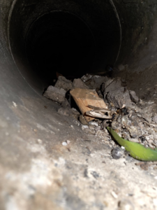 An air duct containing construction debris and dirt, needing cleaning by Affordable Quality Air Duct Cleaning in Denver, CO