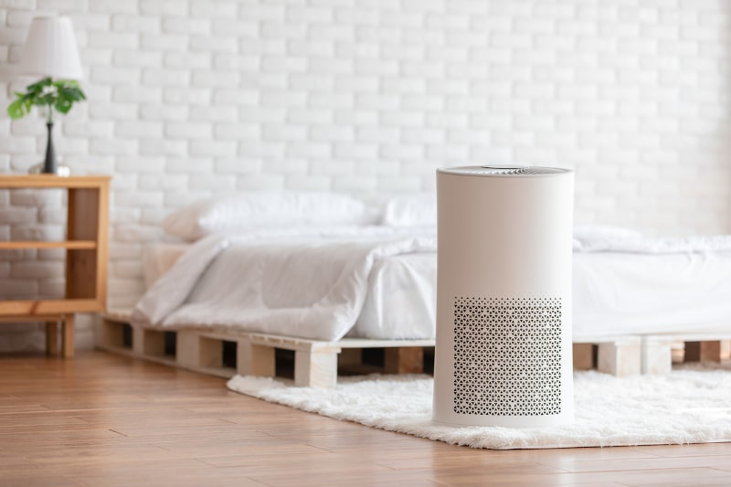 A modern air purifier operating in a clean bedroom, demonstrating indoor air quality services by Climate Control in San Antonio, TX
