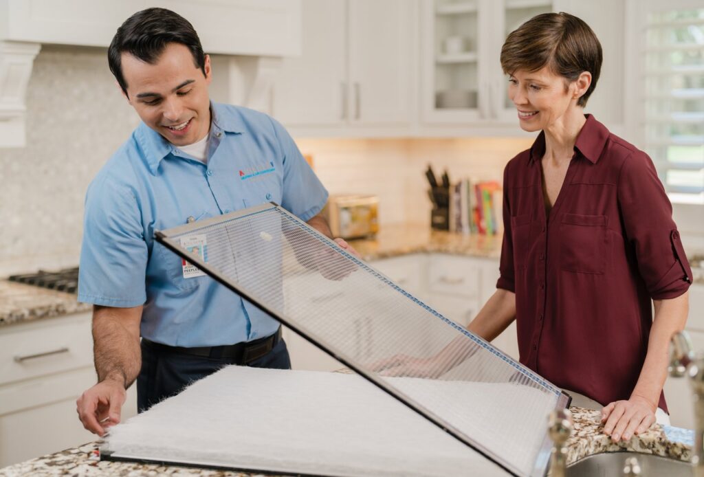 An Aire Serv technician showing a dirty air filter to a female customer during an HVAC service in Billings, MT.