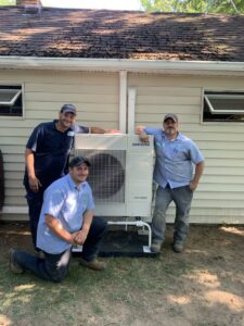 Three Aire Serv technicians posing with a newly installed Samsung mini-split unit in Rochester, NY