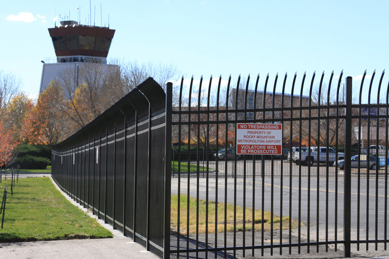 A black metal security fence with a 'No Trespassing' sign at an airport, installed by Life Time Fence, Inc. in Cedar Rapids, IA.