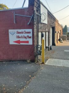 Exterior view of Alameda Cleaners Office & Rug Plant building in Portland, OR, with a directional sign.