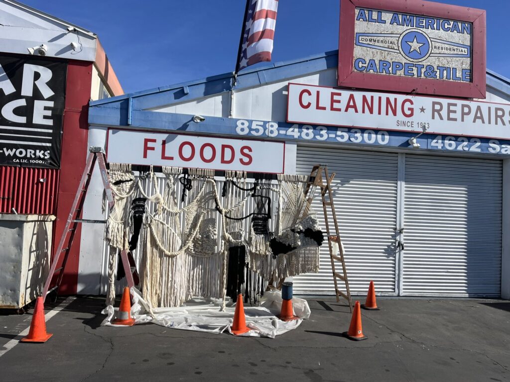 The All American Carpet & Tile storefront with a 'FLOODS' sign, indicating emergency services in San Diego, CA