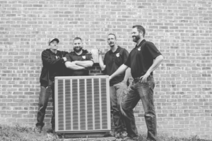 Four Ally Heating and Air technicians standing with an outdoor AC unit in Springfield, MO.