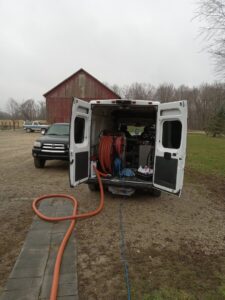 Alpha Clean service van with rear doors open and hoses extended for a carpet cleaning job in Fort Wayne, IN.