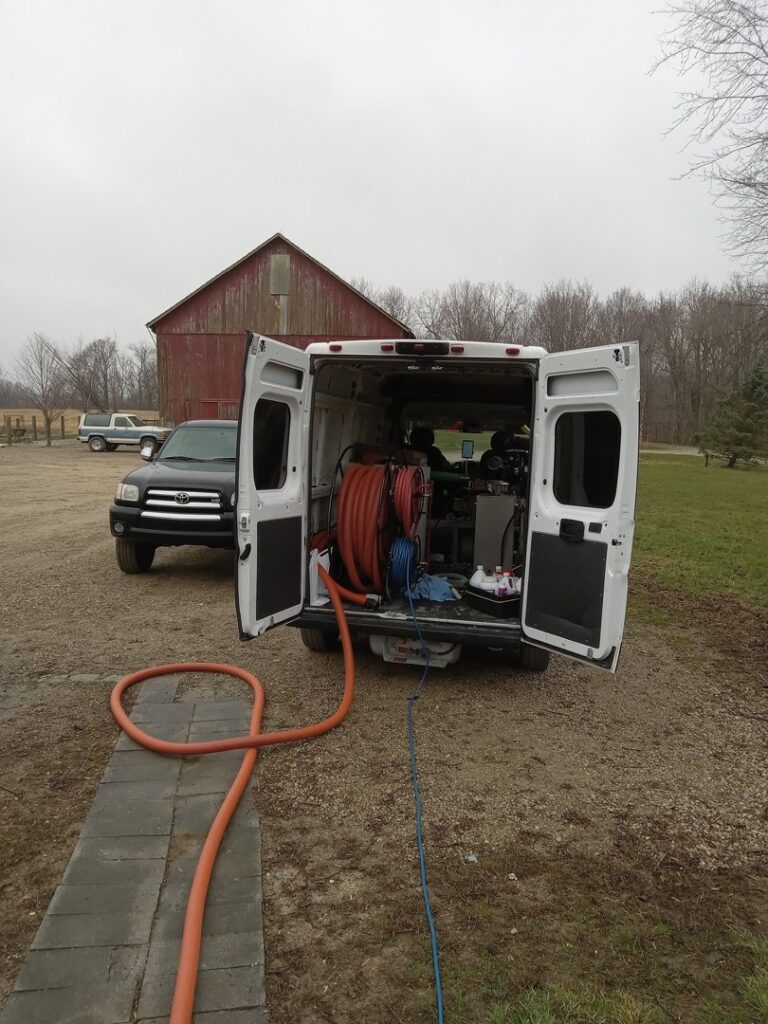 Alpha Clean service van with rear doors open and hoses extended for a carpet cleaning job in Fort Wayne, IN.