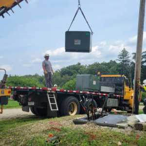 Alpha Electric LLC team installing a large electrical transformer with a crane in Dover, NH.