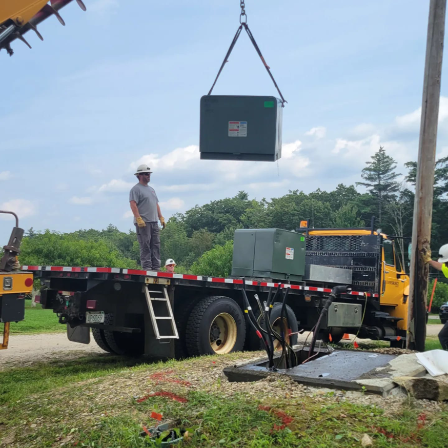 Alpha Electric LLC team installing a large electrical transformer with a crane in Dover, NH.