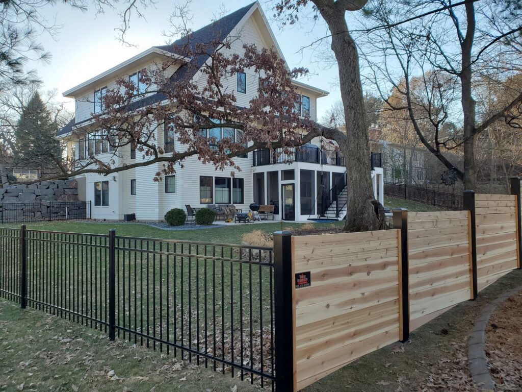 A modern fence combining black aluminum and horizontal wood slats around a home by Top Notch Fence in East Bethel, MN